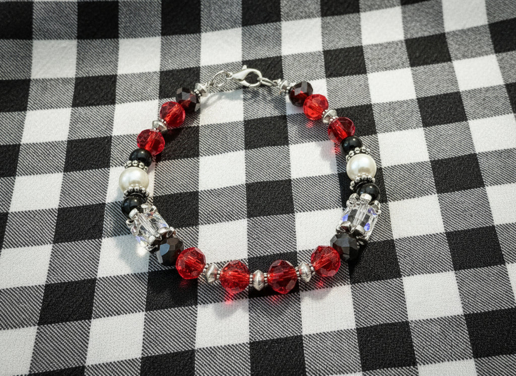 Beaded bracelet with red, black, and white beads on a dark textured background