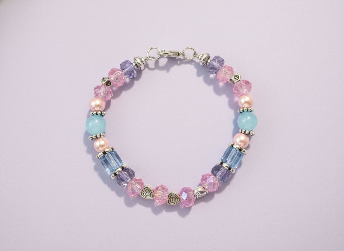 Beaded bracelet with pink, blue, and clear beads on a dark background