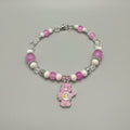 Beaded bracelet with pink and white beads and a bear charm on a black background
