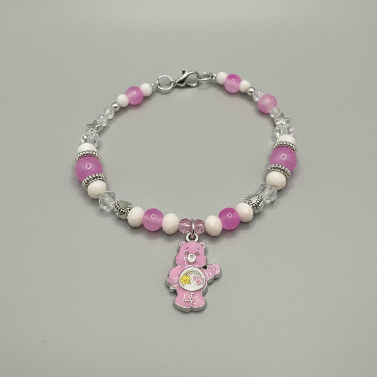Beaded bracelet with pink and white beads and a bear charm on a black background