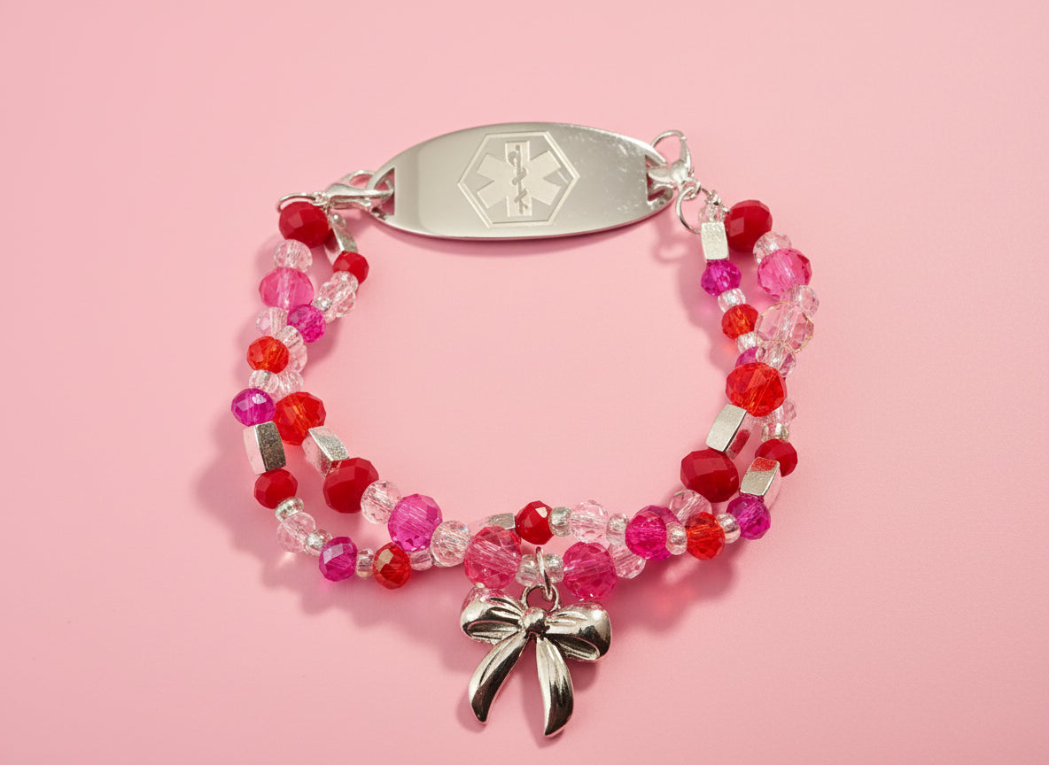 Beaded bracelet with a bow charm and medical alert tag on a black background