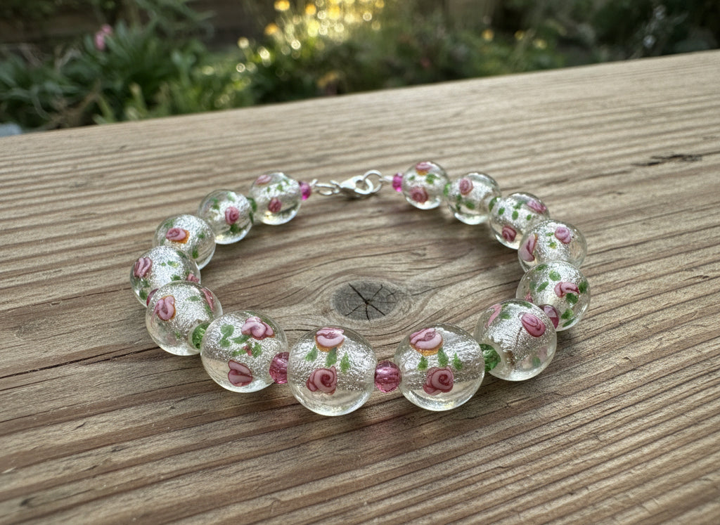 Bracelet with transparent beads featuring floral designs on a black background