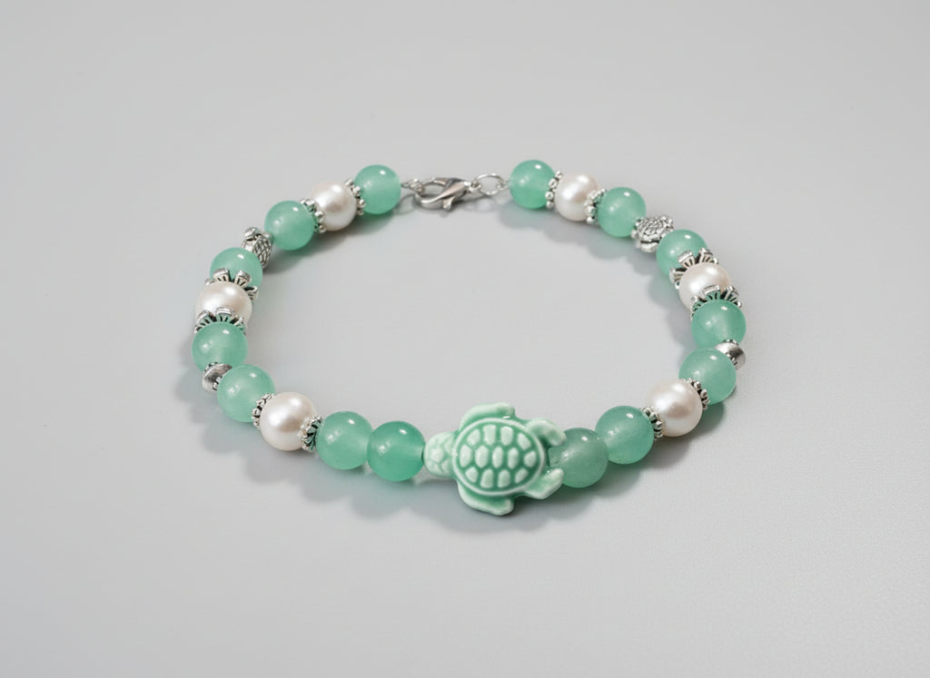 Bracelet with green beads and a turtle charm on a black background