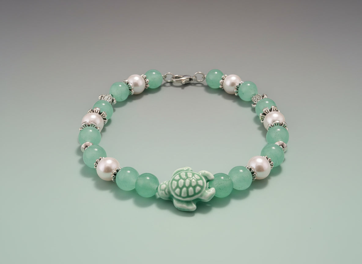 Beaded bracelet with green and pink beads and a turtle charm on a dark background