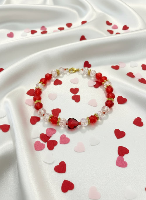 Bracelet with red, clear, and gold beads on a dark textured background