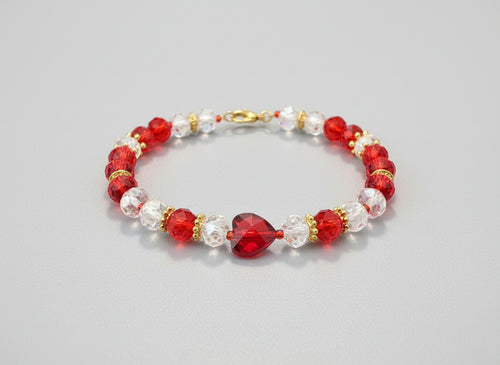 Beaded bracelet with red, clear, and gold beads on a dark textured surface