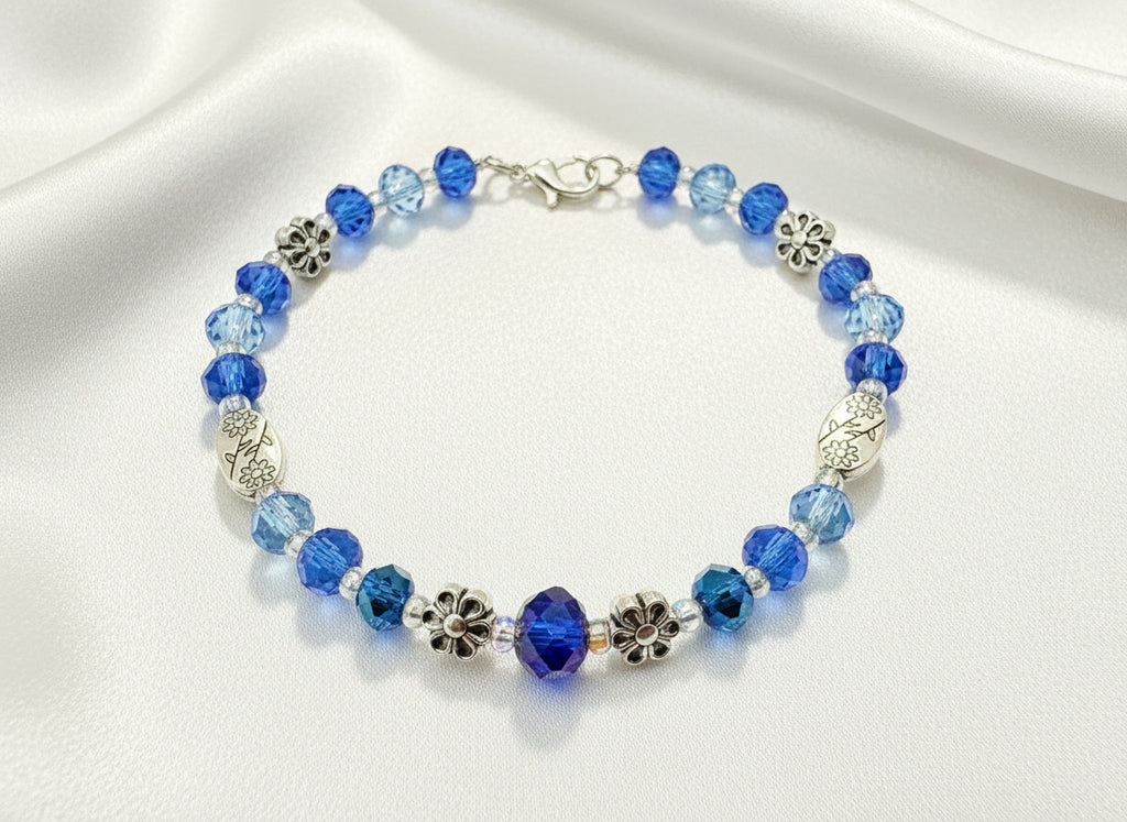 Blue beaded bracelet with silver charms on a dark background