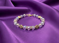 Bracelet with purple beads and gold accents on a dark textured background