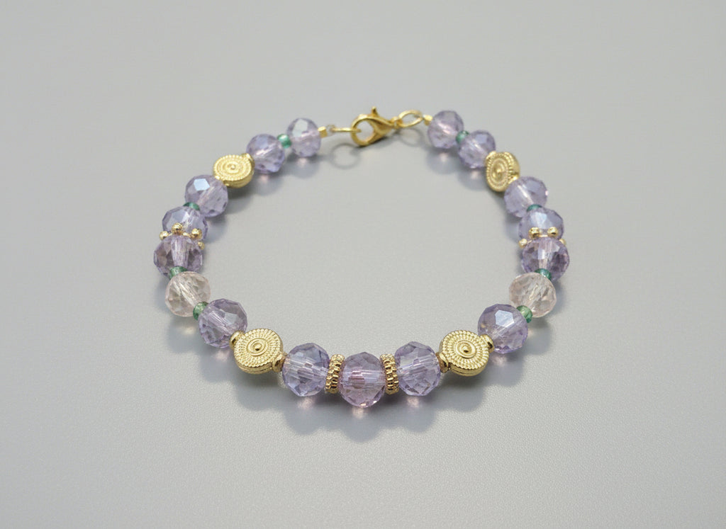 Bracelet with purple beads and gold accents on a dark textured background