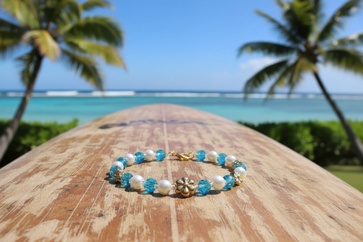 Beaded bracelet with blue and white beads and gold flower charms on a dark background