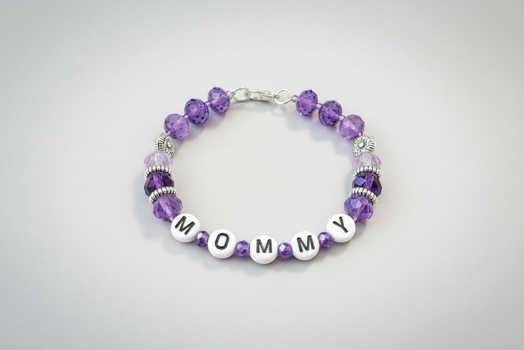 Bracelet with purple beads and letter beads spelling 'MOM' on a dark background