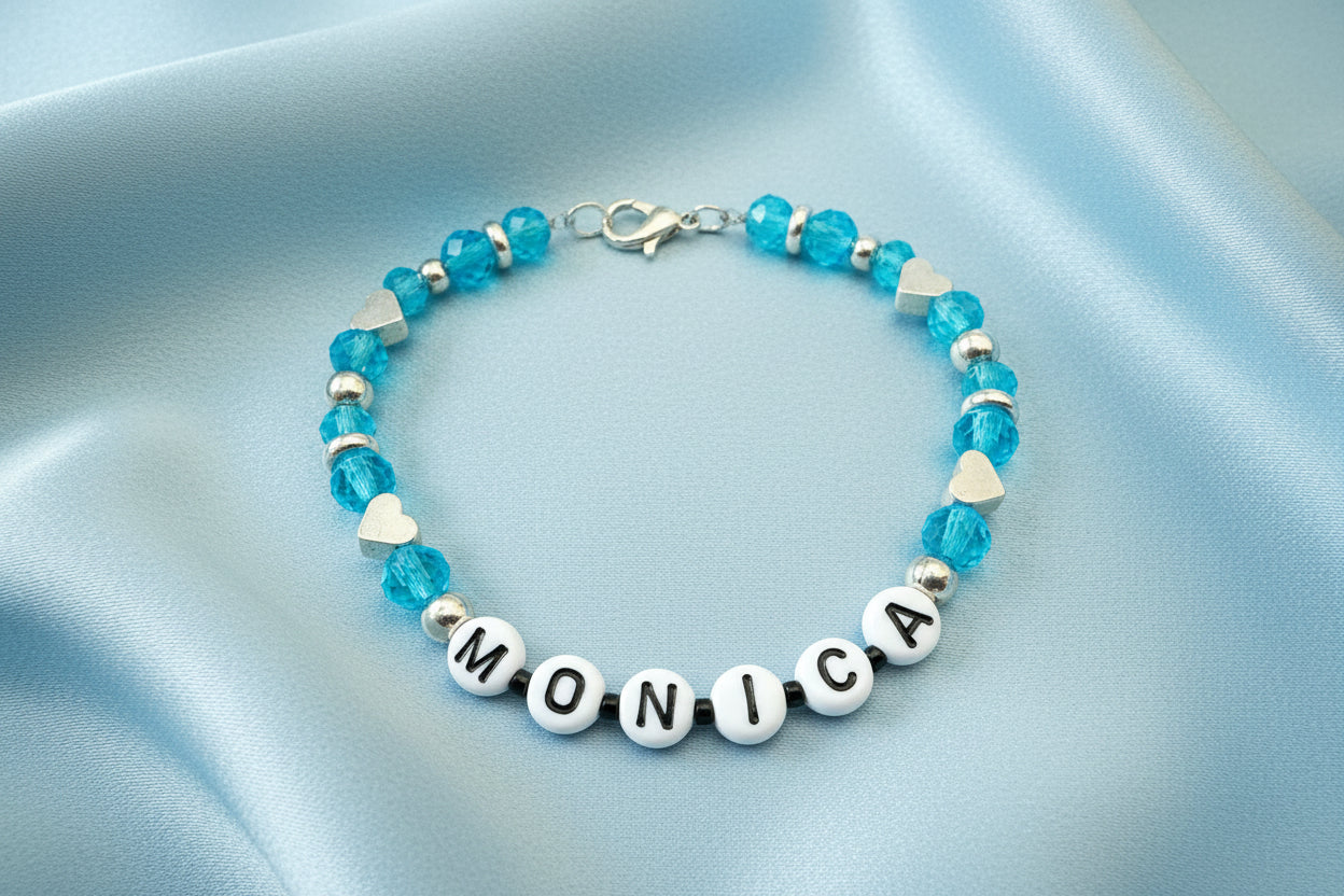 Bracelet with blue beads and letter beads spelling 'MONICA' on a dark background