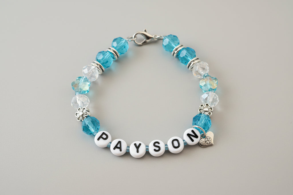 Bracelet with blue and clear beads and a name charm on a dark surface