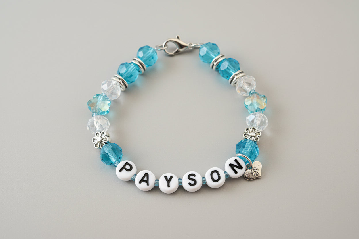 Bracelet with blue and clear beads and a name charm on a dark surface