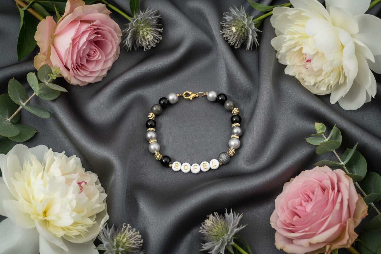 Bracelet with purple and white beads on a purple fabric background with flowers