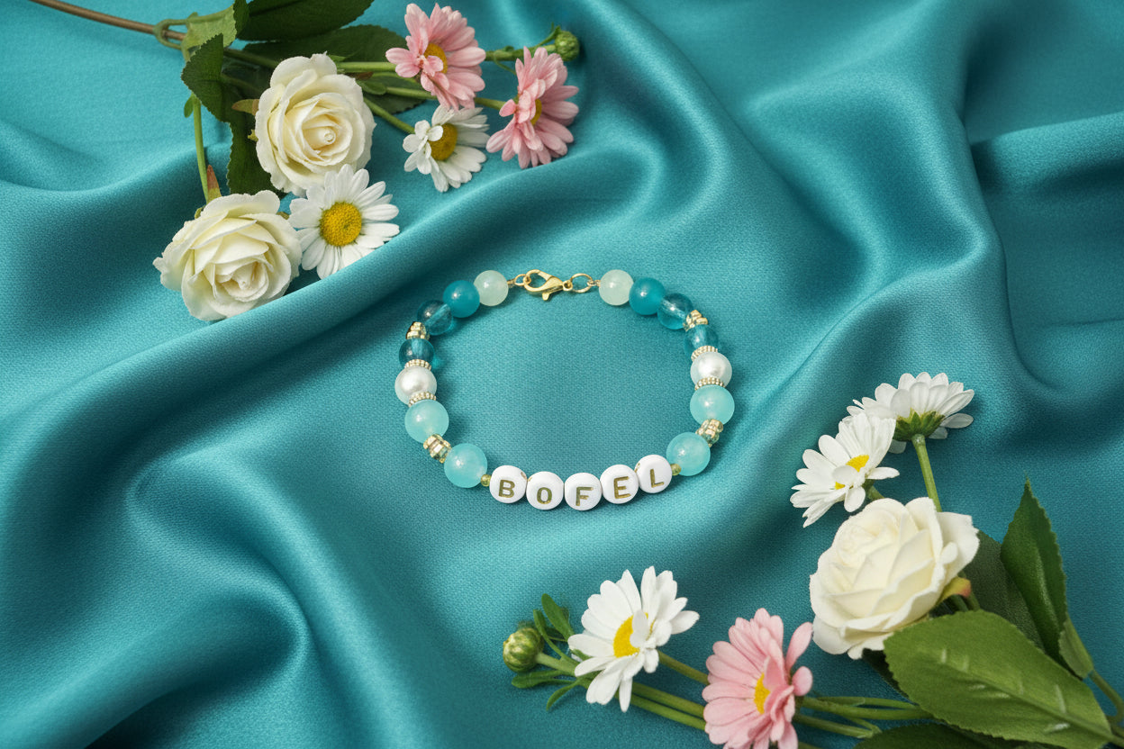 Pink bracelet with letter beads on a white fabric background surrounded by flowers