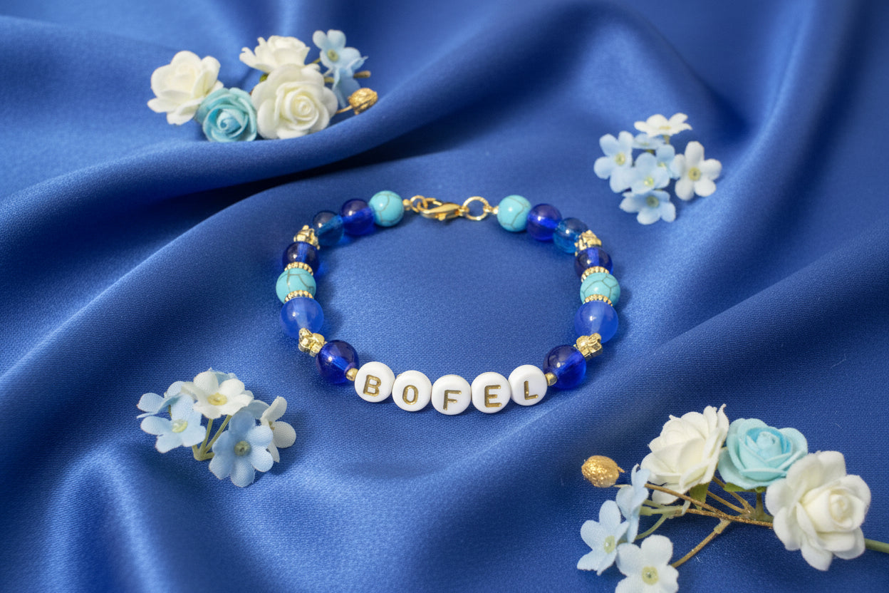 Bracelet with letter beads spelling 'BOFEL' on a dark fabric background