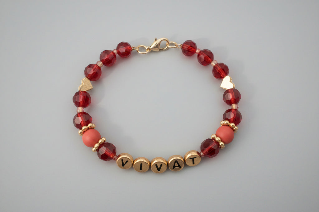 Bracelet with colorful beads and 'VIVAT' charm on a dark background