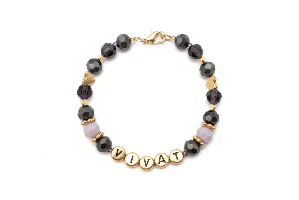 Bracelet with beads and gold letters spelling 'VIVA' on a dark background