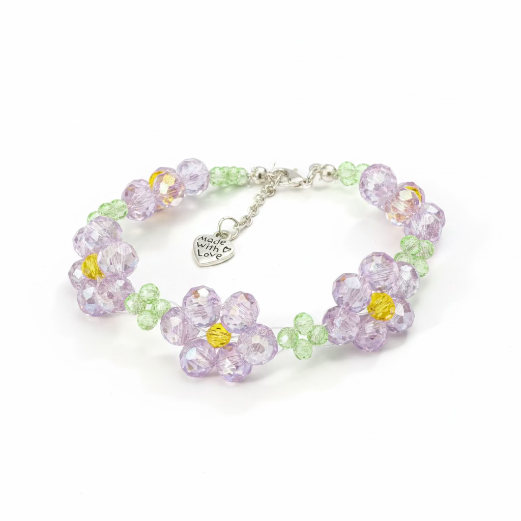 A beaded bracelet featuring faceted flower-shaped beads in lavender, light green, and yellow, with a silver-tone clasp and heart charm, displayed on a black textured fabric background.