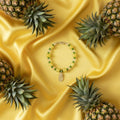 Beaded bracelet with pineapple charm on a gray background