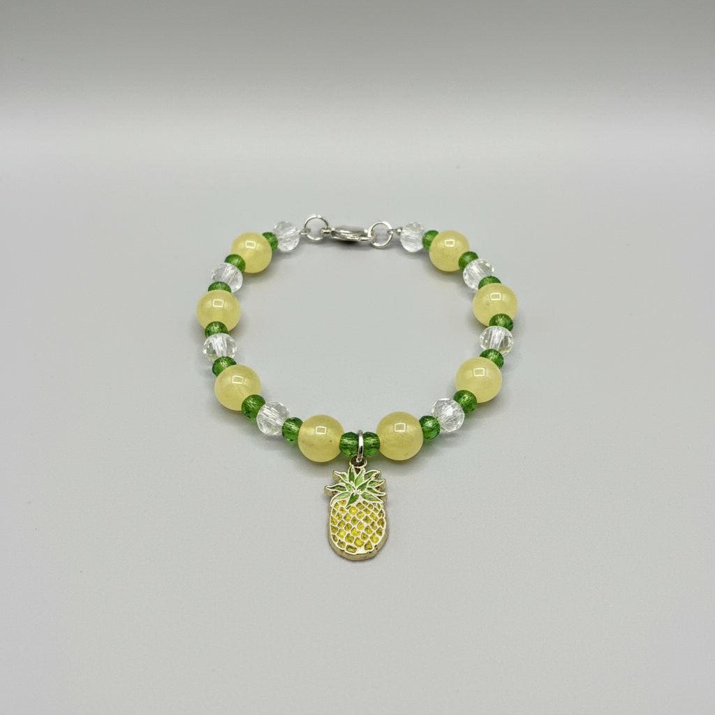 Bracelet with yellow and green beads and pineapple charm on a dark background