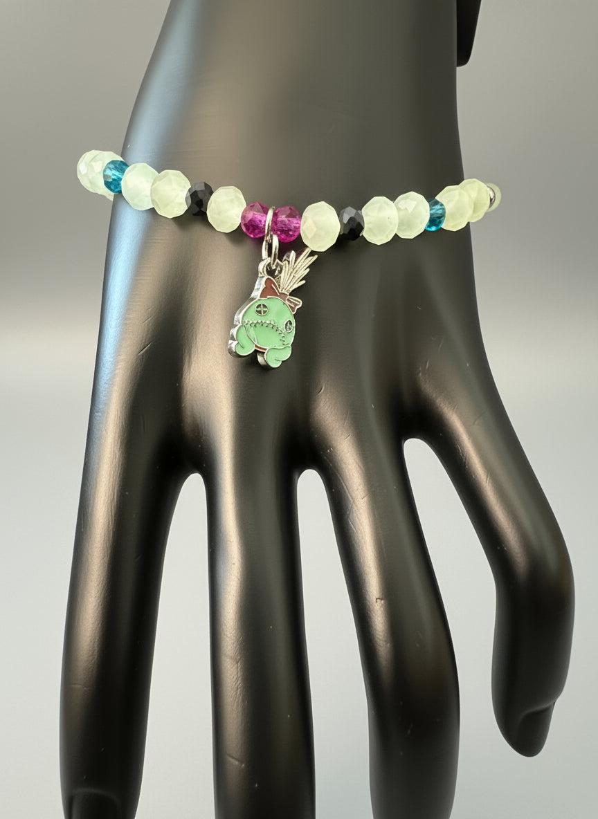 Bracelet with colorful beads and a green charm on a car seat.