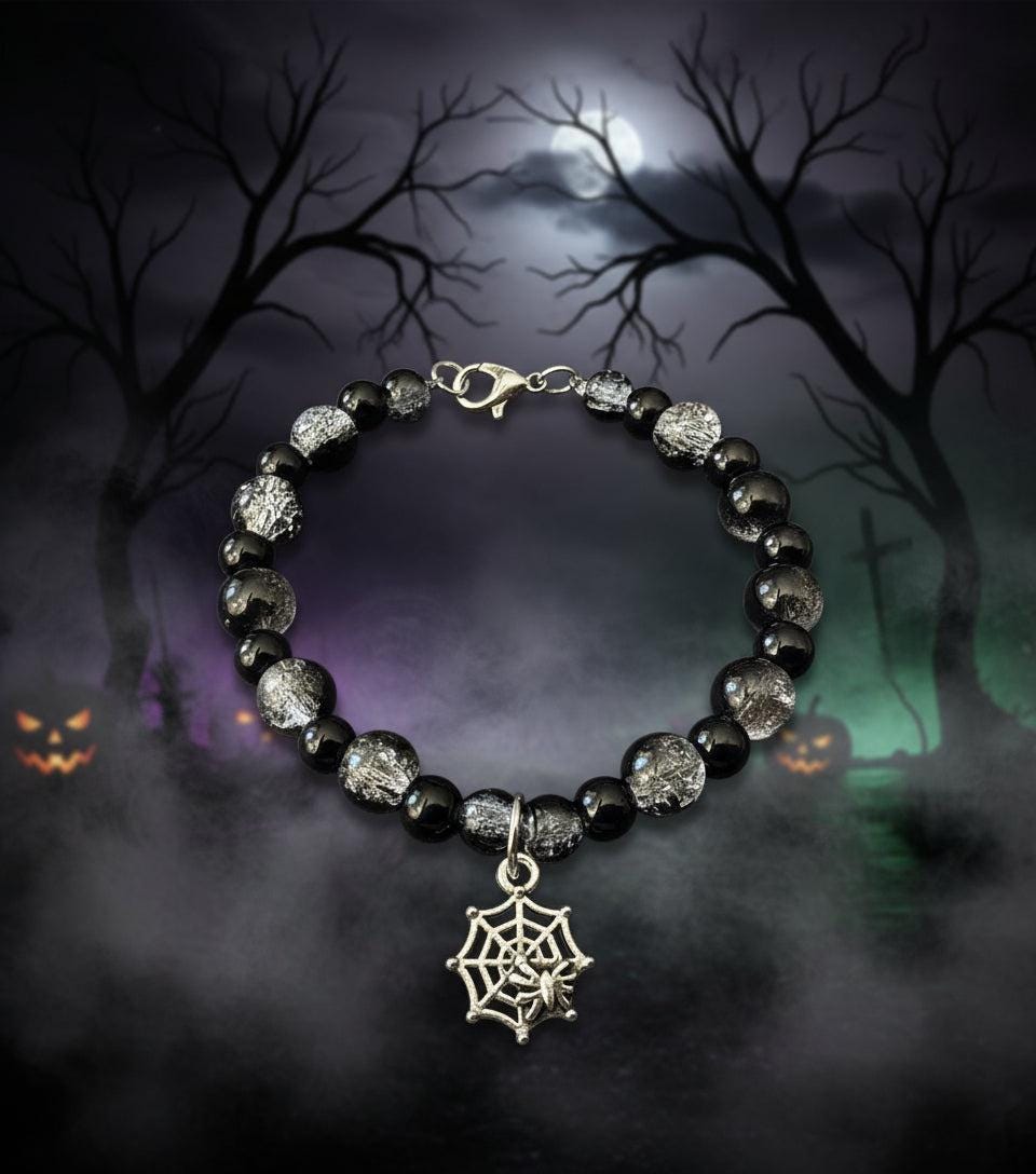 Black beaded bracelet with a silver spider web charm on a dark background