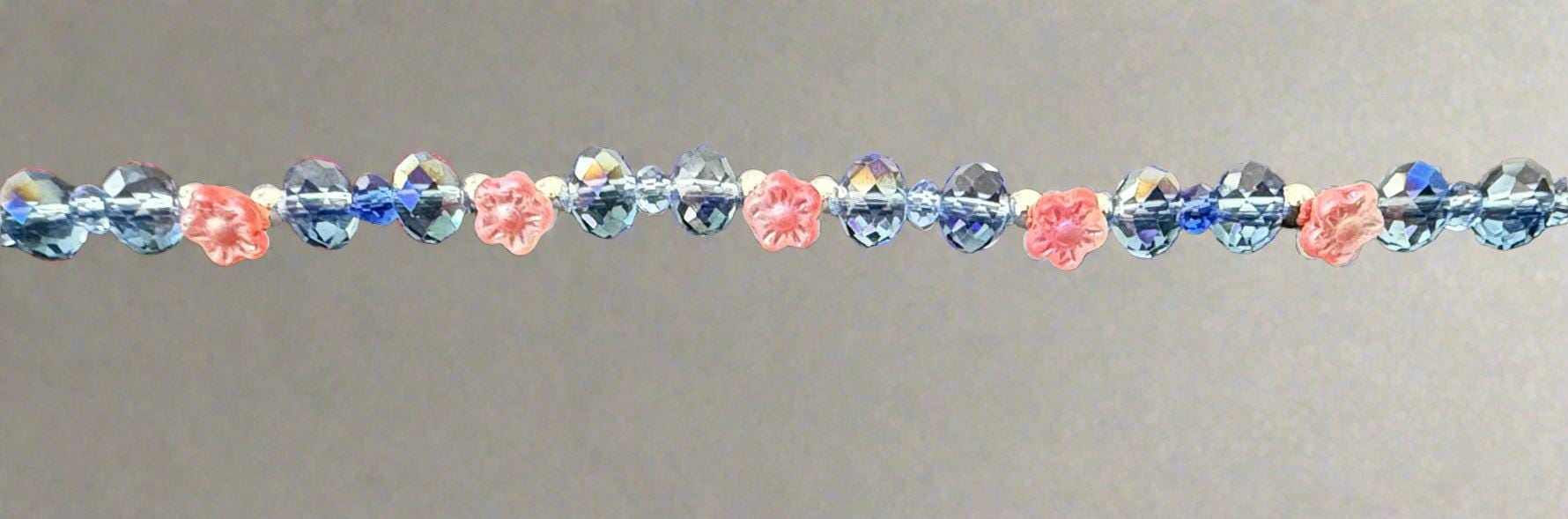 Beaded bracelet with pink and blue beads on a textured gray background