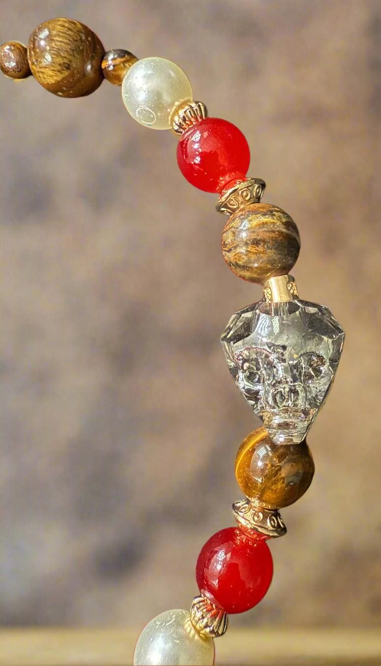 Close-up of a beaded necklace with red, white, and brown beads on a dark fabric background