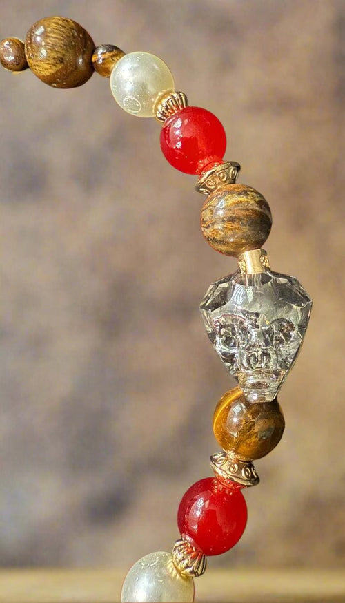Close-up of a beaded necklace with red, white, and brown beads on a dark fabric background