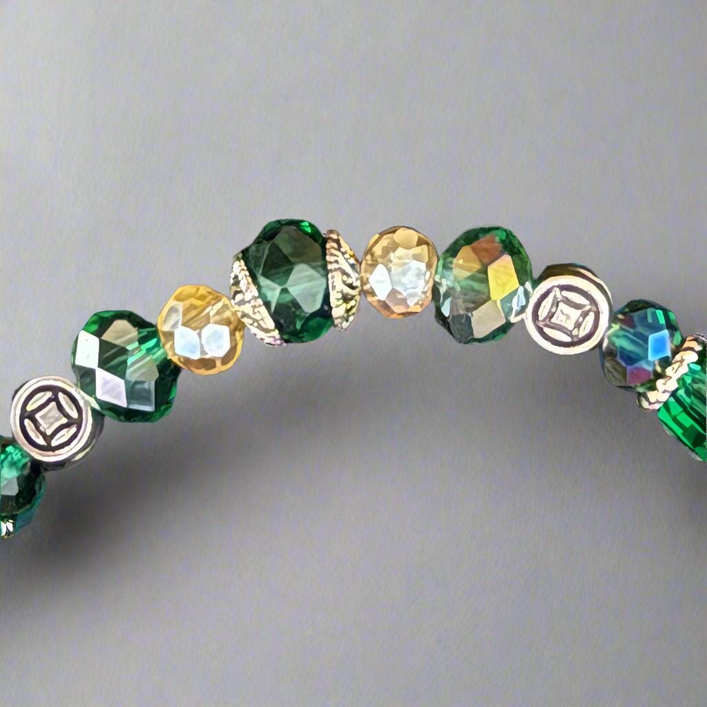 Beaded bracelet with green, gold, and silver beads on a dark textured background