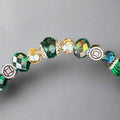 Beaded bracelet with green, gold, and silver beads on a dark textured background