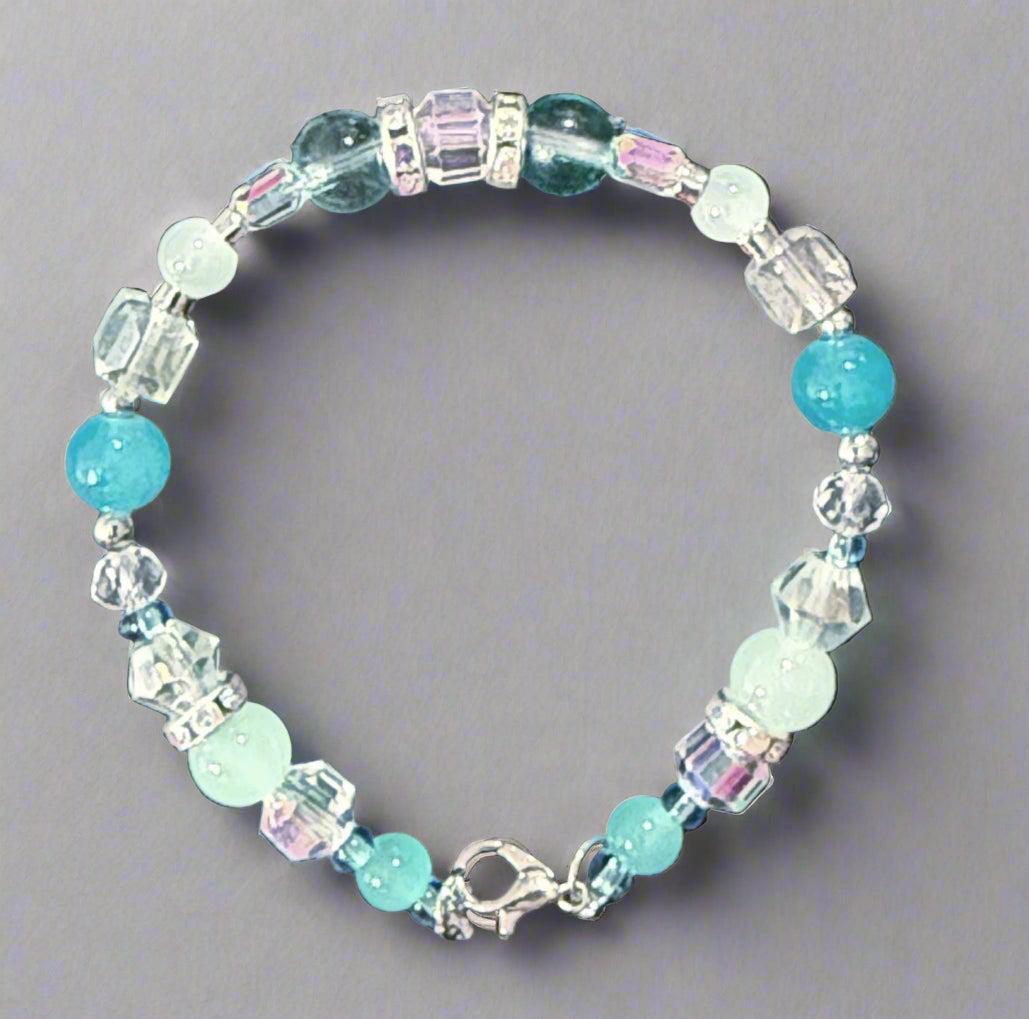 Beaded bracelet with blue and clear beads on a dark fabric background