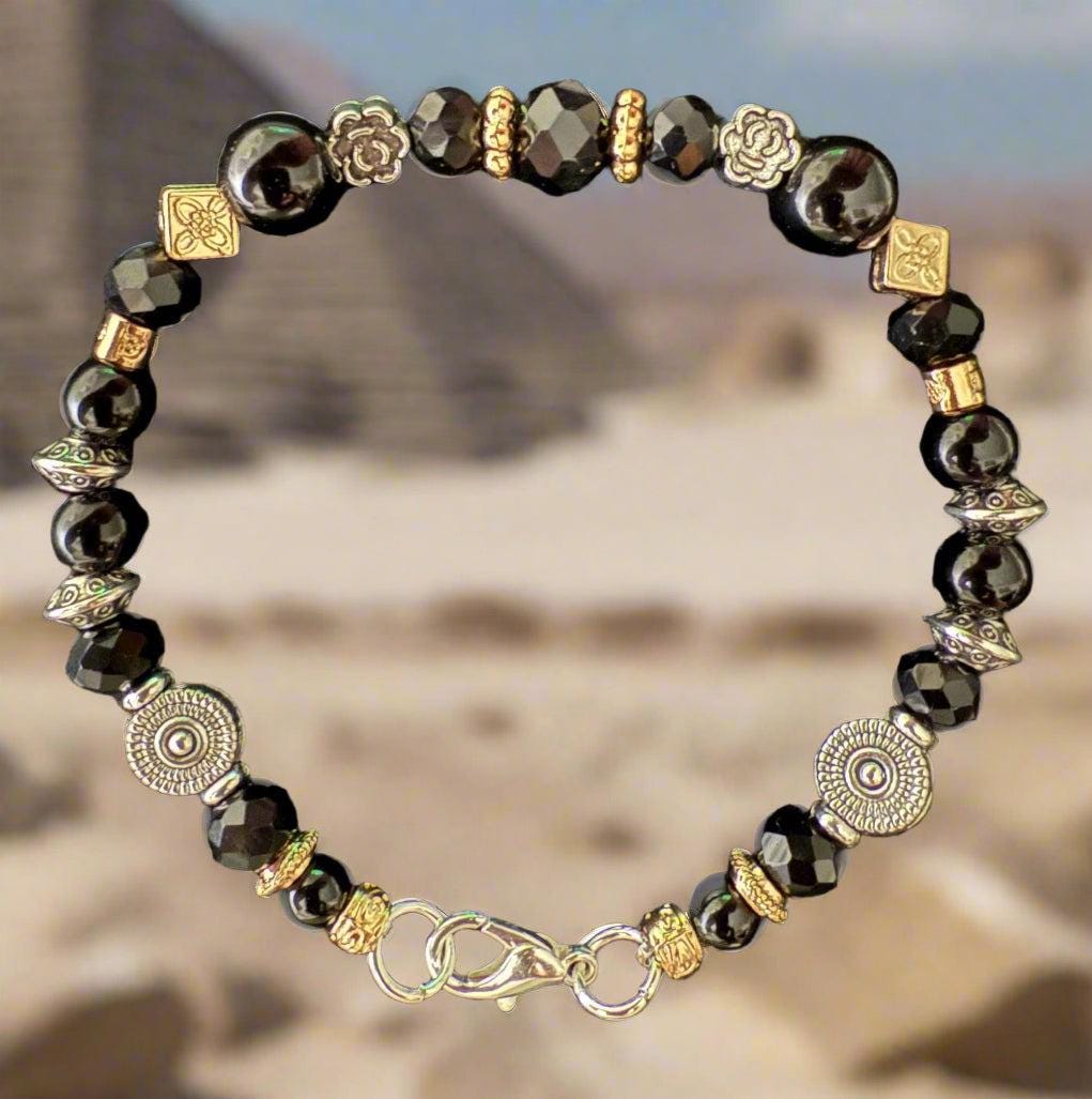 Bracelet with black beads and gold accents on a black background