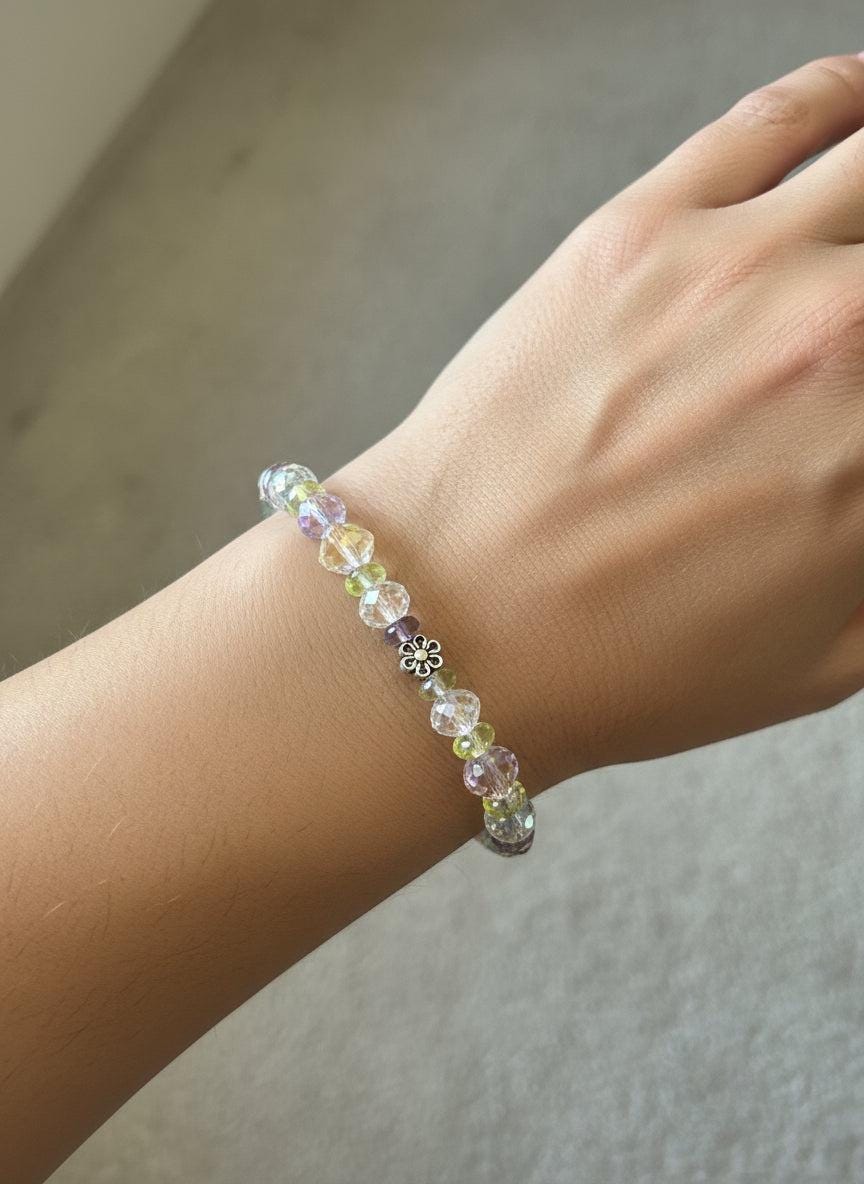 Multicolored beaded bracelet on a black mannequin hand against a dark background