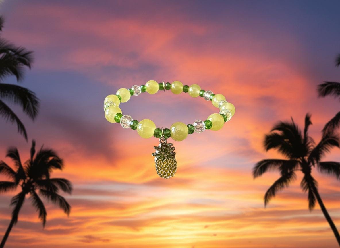 Bracelet with green and yellow beads and a pineapple charm on a dark surface
