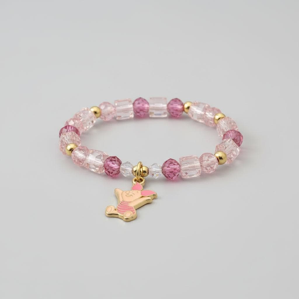 Bracelet with pink and clear beads and a pink dog charm on a dark surface