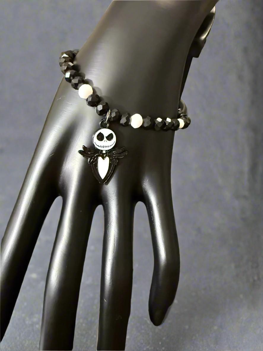 Black beaded bracelet with a skull charm on a black mannequin hand.