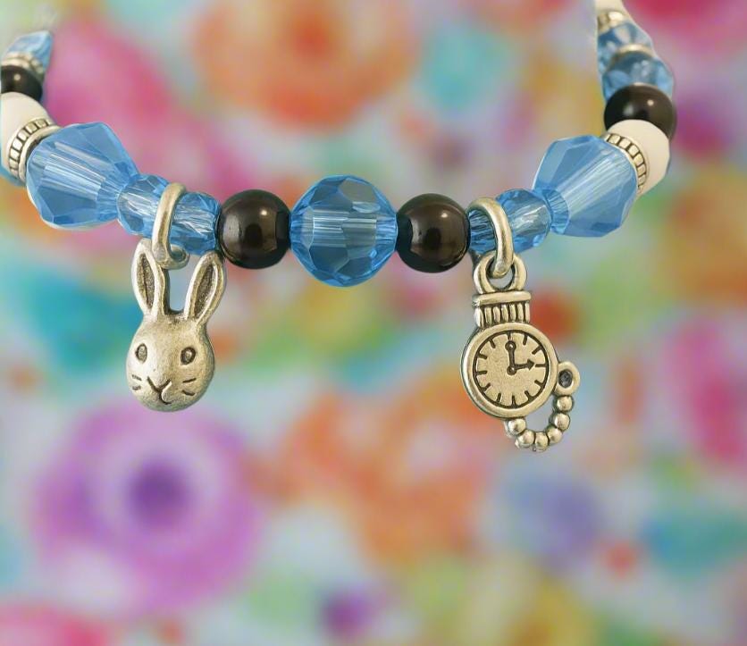 Bracelet with rabbit and clock charm on a green mannequin arm.