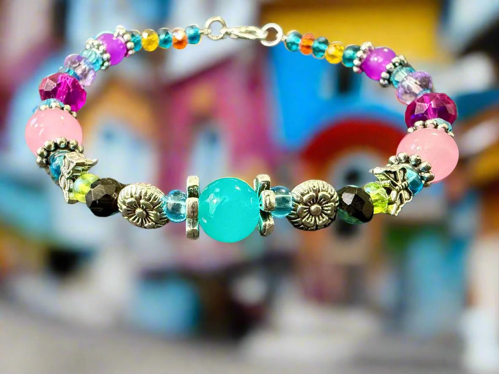 Colorful beaded bracelet with a turquoise center stone on a textured surface