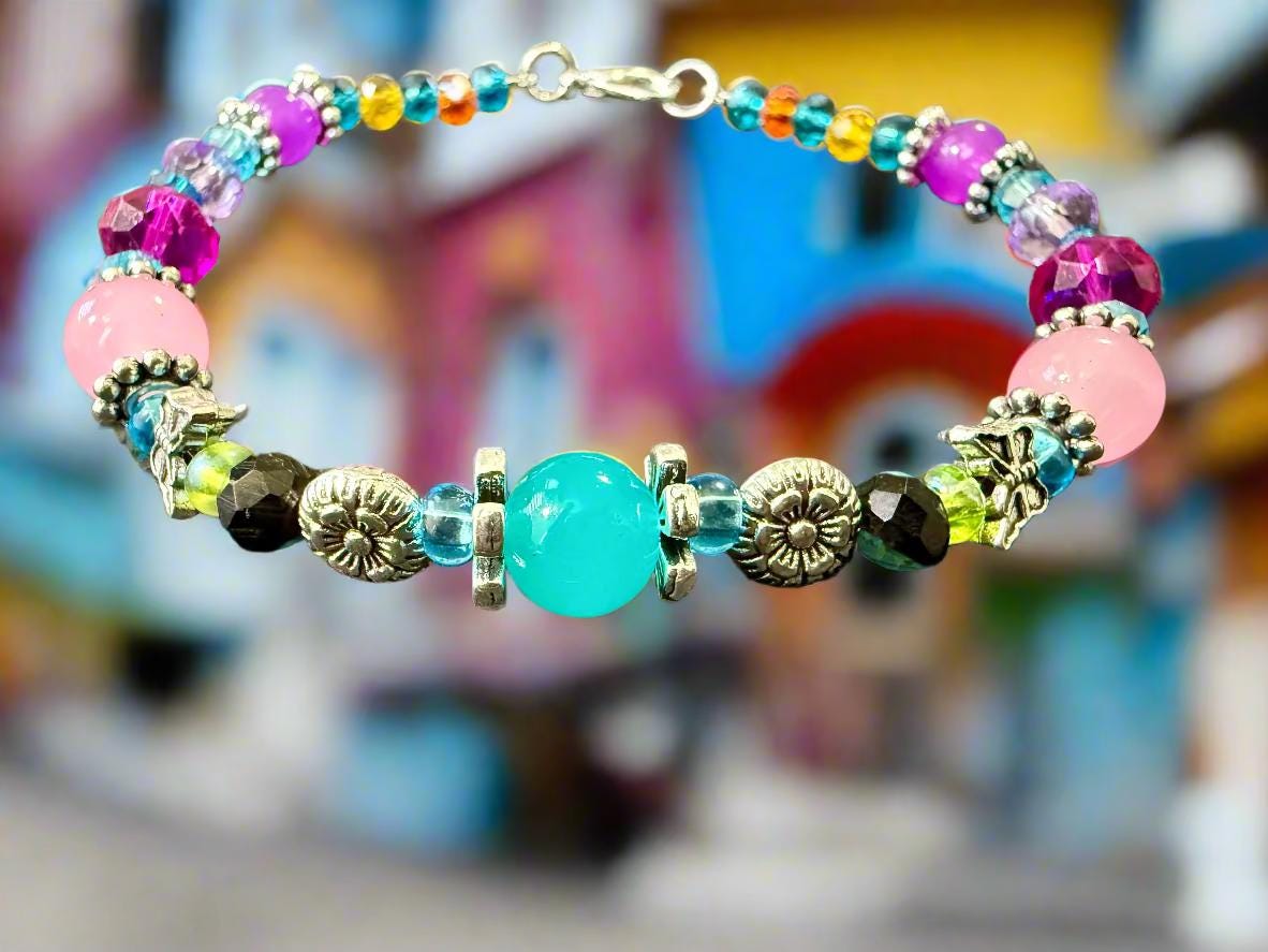 Colorful beaded bracelet with a turquoise center stone on a textured surface