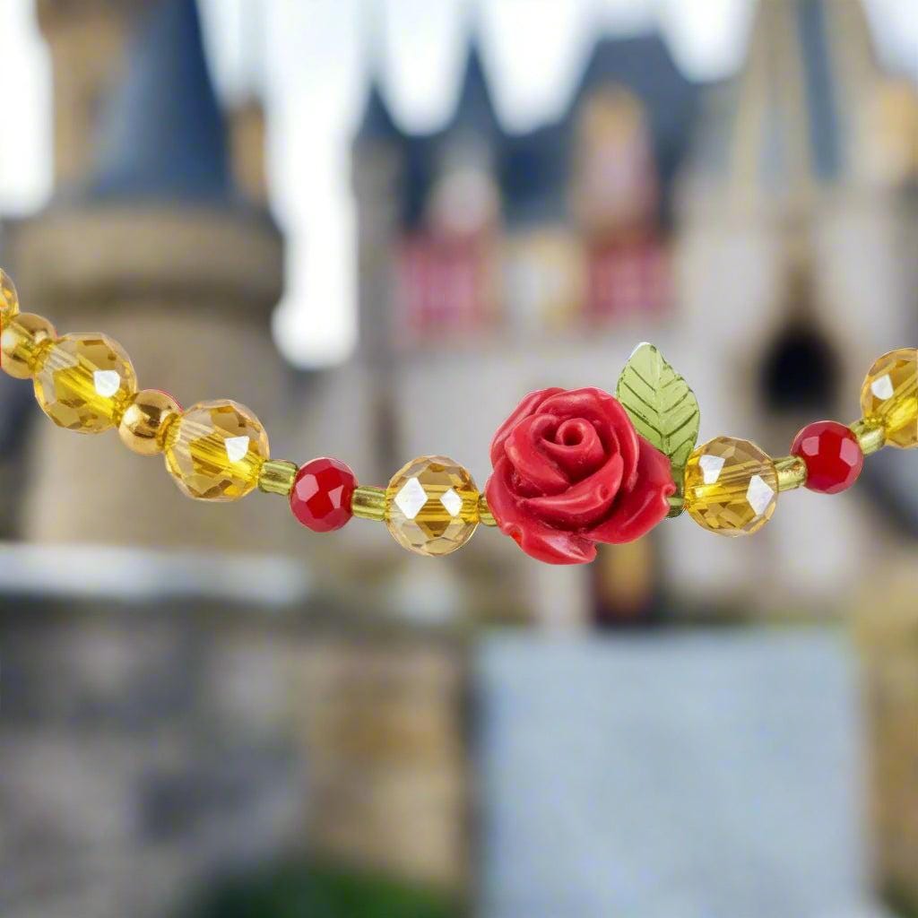 Necklace with red rose, green leaves, and yellow beads on a black textured background